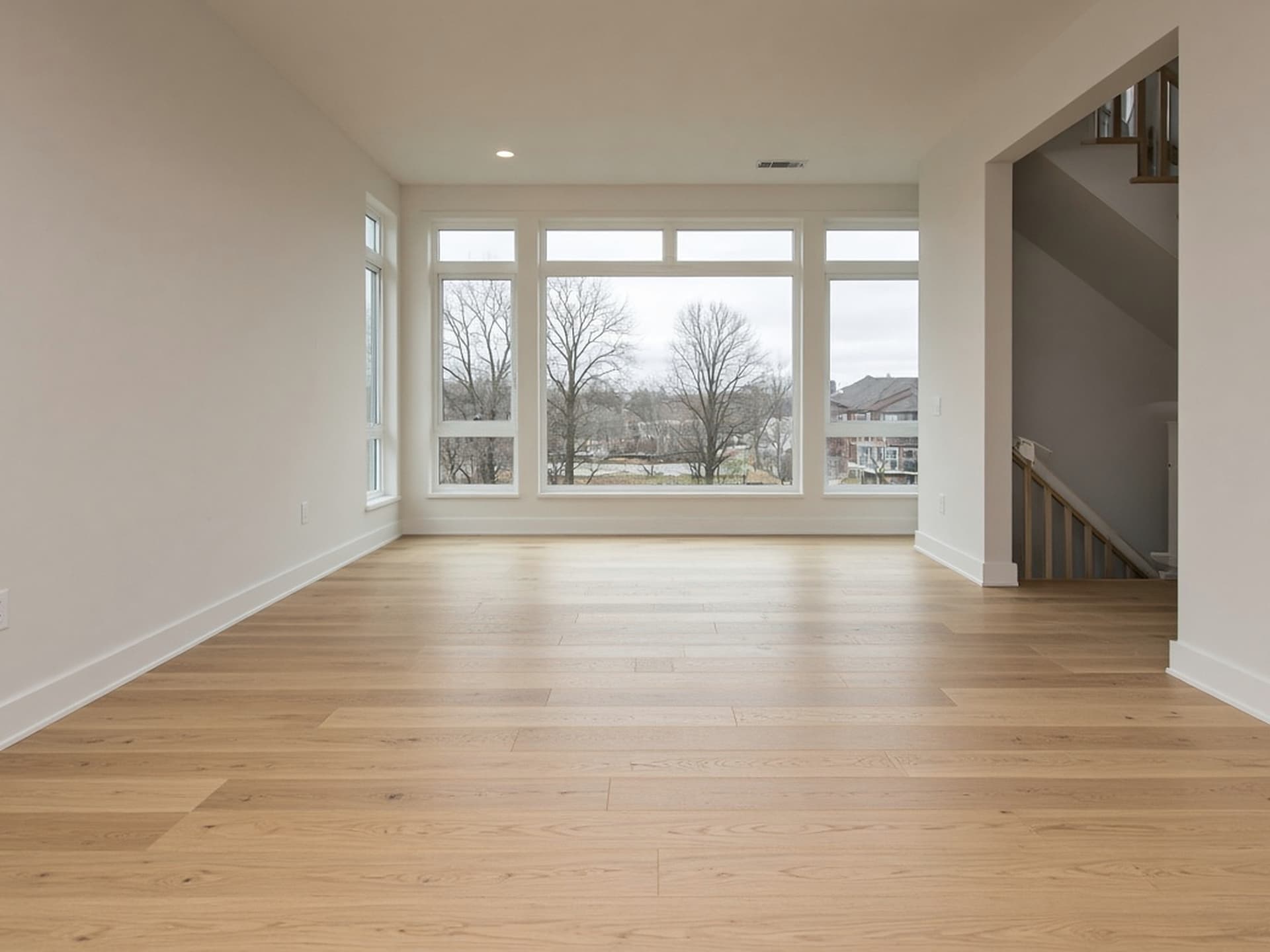 The same floor with wide-plank white oak installed and site-finished, running toward the windows.